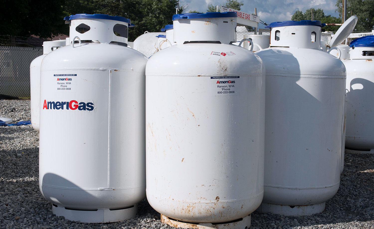 Several 120 gallon size propane tanks standing upright